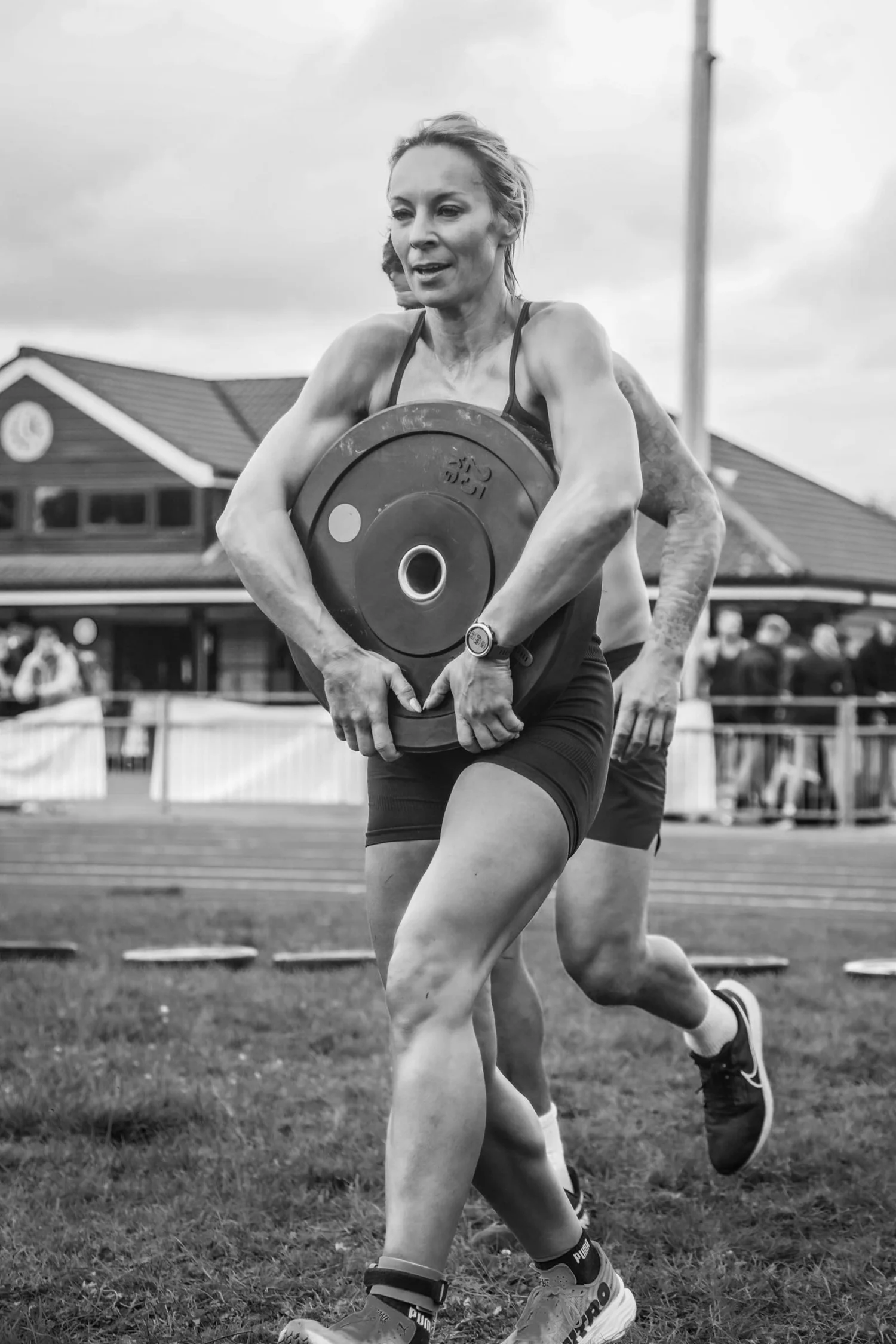 Atleta che trasporta un disco di peso davanti al corpo nella posizione “Front Carry Labour”
